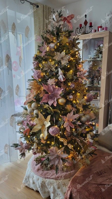 Künstlicher Weihnachtsbaum, grün, verziert mit weißen und rosafarbenen Ornamenten, im Wohnzimmer