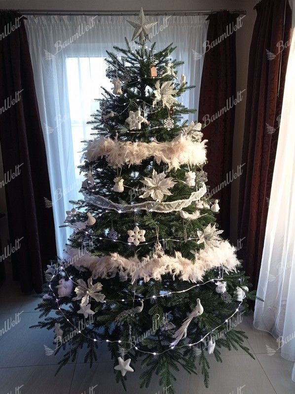 Künstlicher Weihnachtsbaum groß und massiv, verziert mit weißen Ornamenten im Wohnzimmer