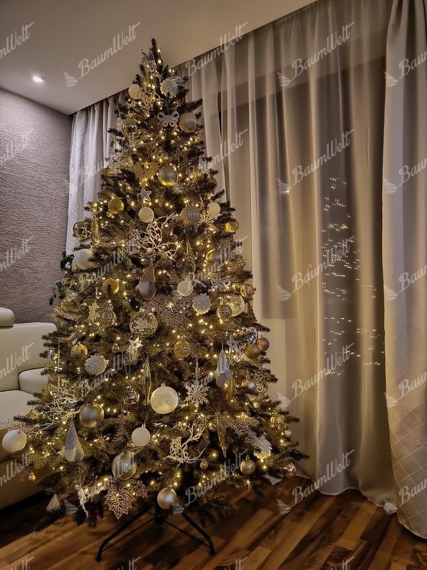 Künstlicher grüner Weihnachtsbaum, geschmückt mit weißen und goldenen Weihnachtsdekorationen, im Wohnzimmer