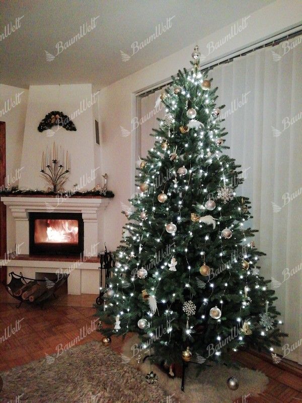 Künstlicher grüner Weihnachtsbaum, geschmückt mit weißen und goldenen Weihnachtsdekorationen, im Wohnzimmer