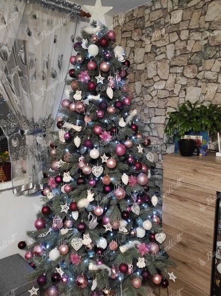 Künstlicher Weihnachtsbaum mit silbergrünen Zweigen, geschmückt mit weiß-violettem Weihnachtsschmuck, im Wohnzimme